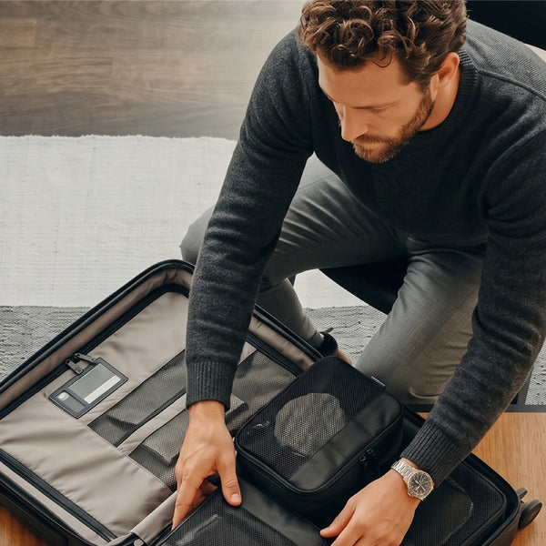 Resenär som packar en resväska med Remodius packing cubes och en reseadapter