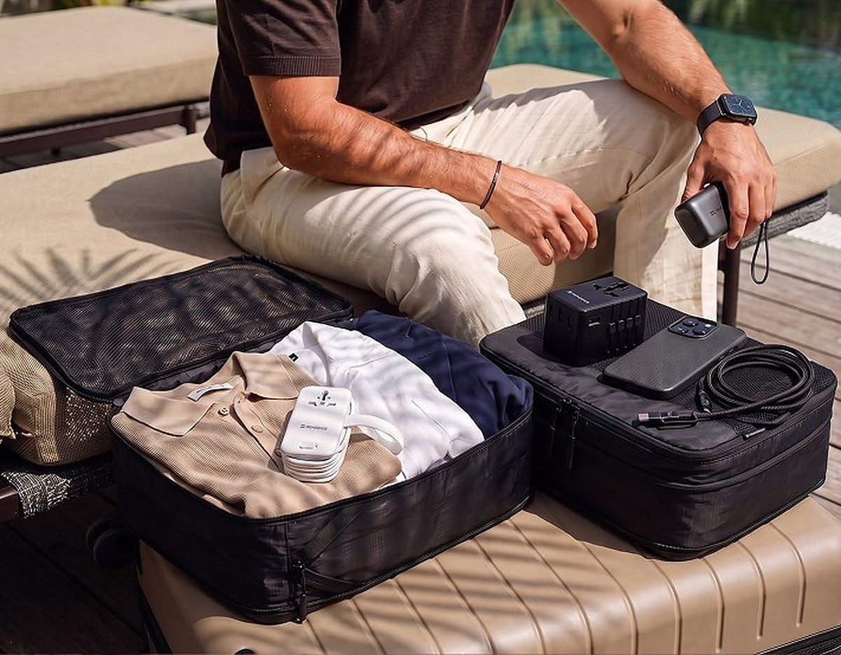 Ingepakte koffer met packing cubes, wereldstekker en powerbank bij het zwembad